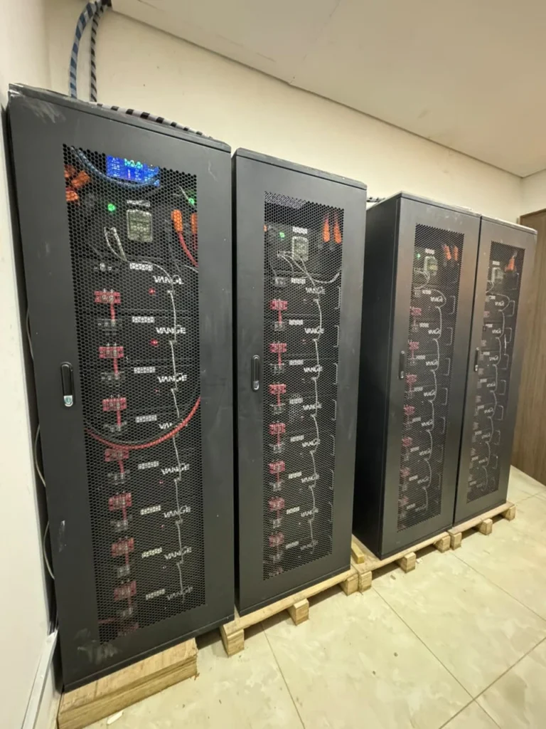 Four tall battery cabinets on pallets in a plant room