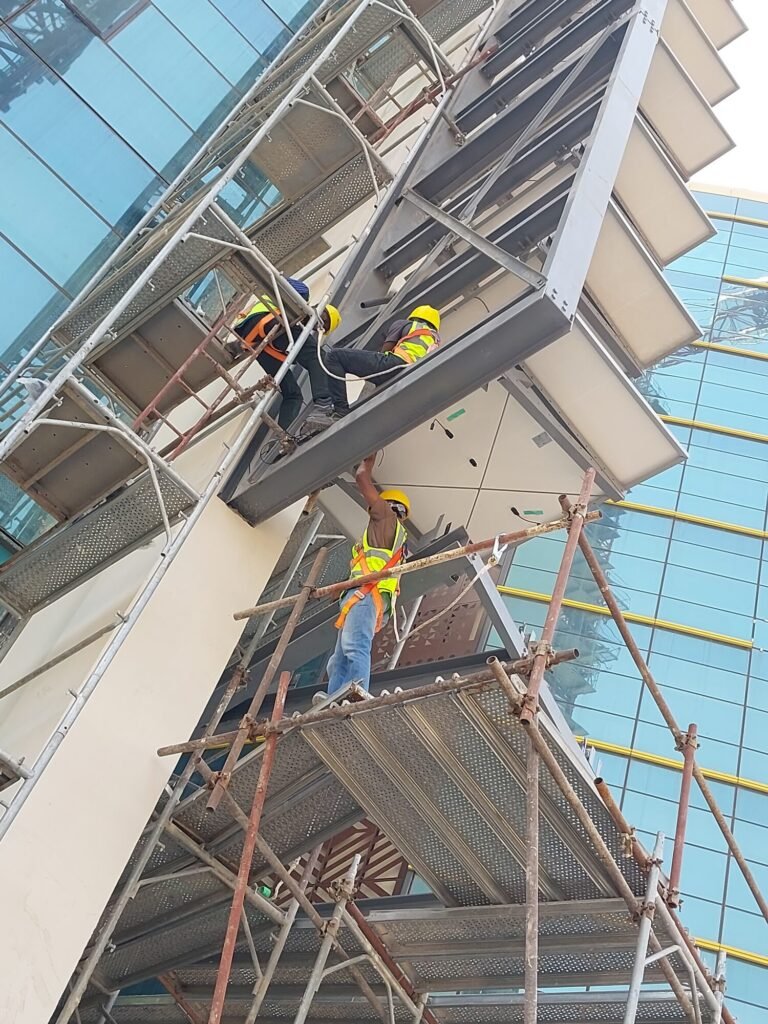McMyra crew installing facade-mounted solar panels from scaffolding on the tower curtain wall