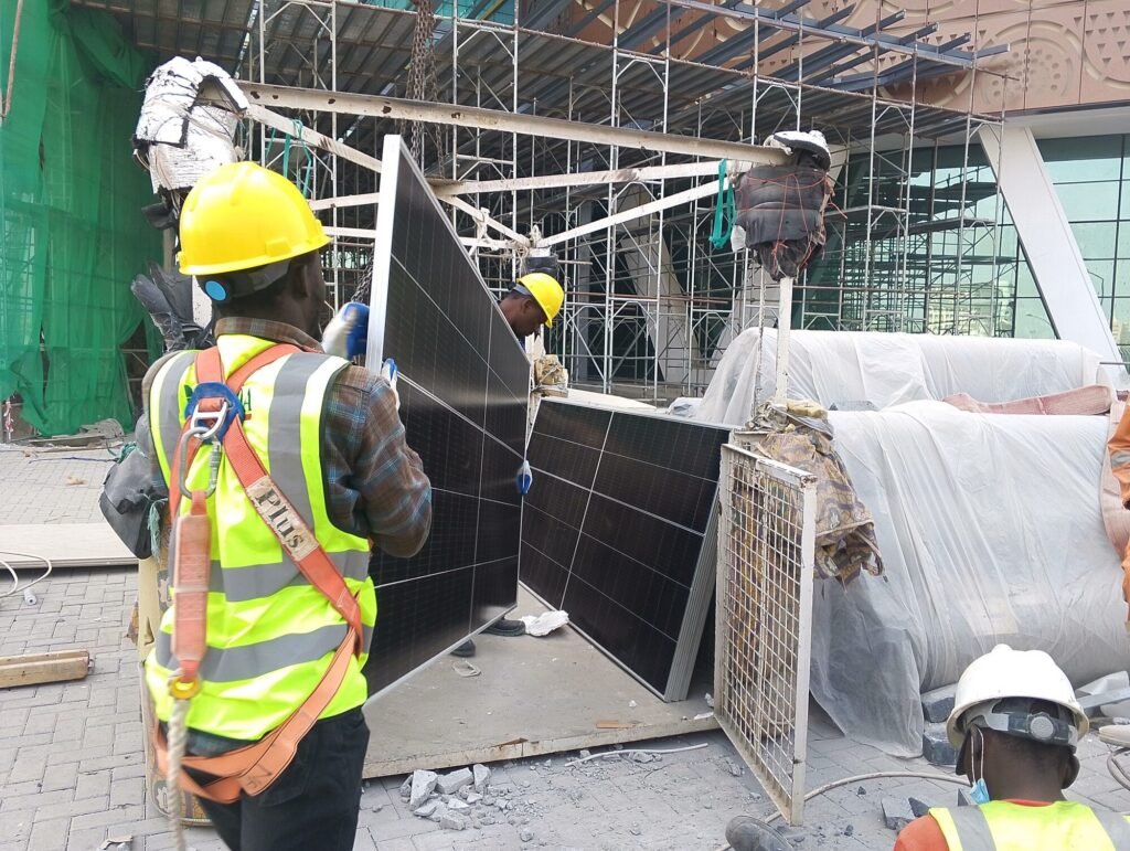Solar modules staged at ground level before being lifted to the facade
