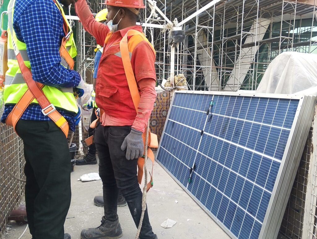 Two crew carrying a solar module across the site