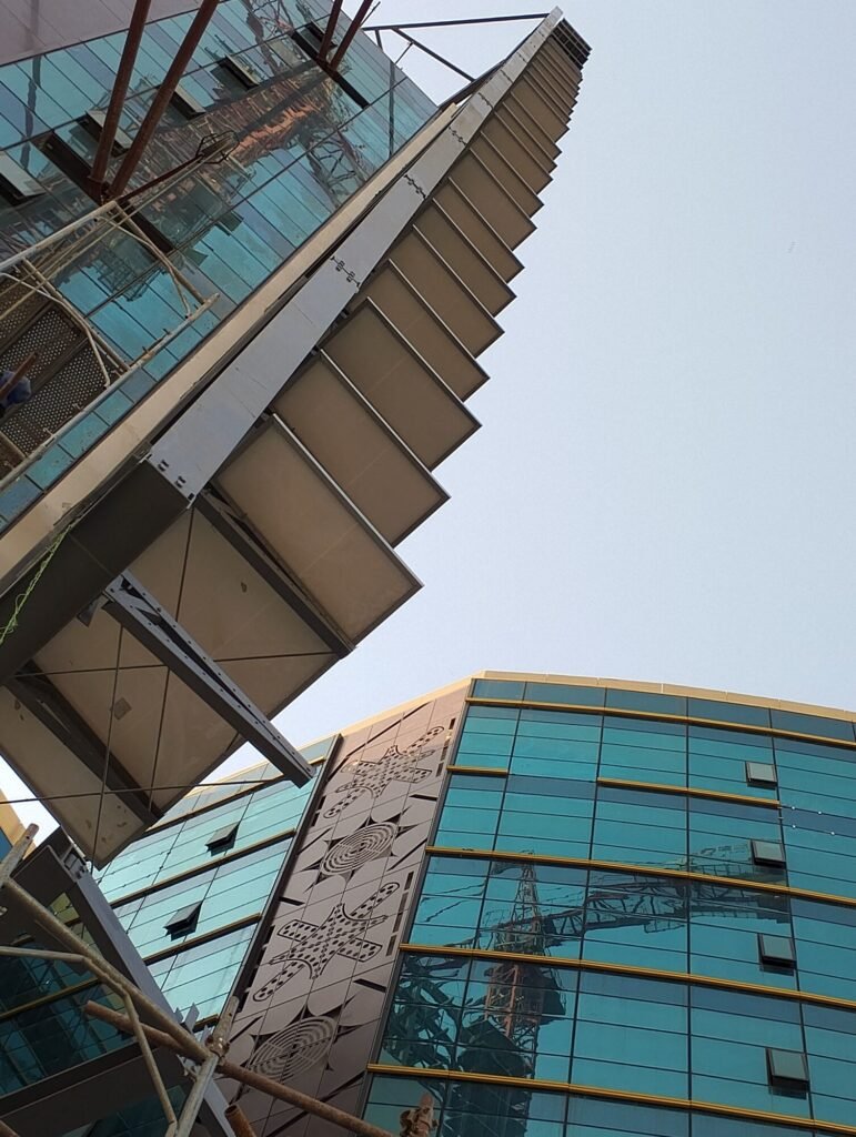 Looking up at the completed facade-mounted array against the glass tower
