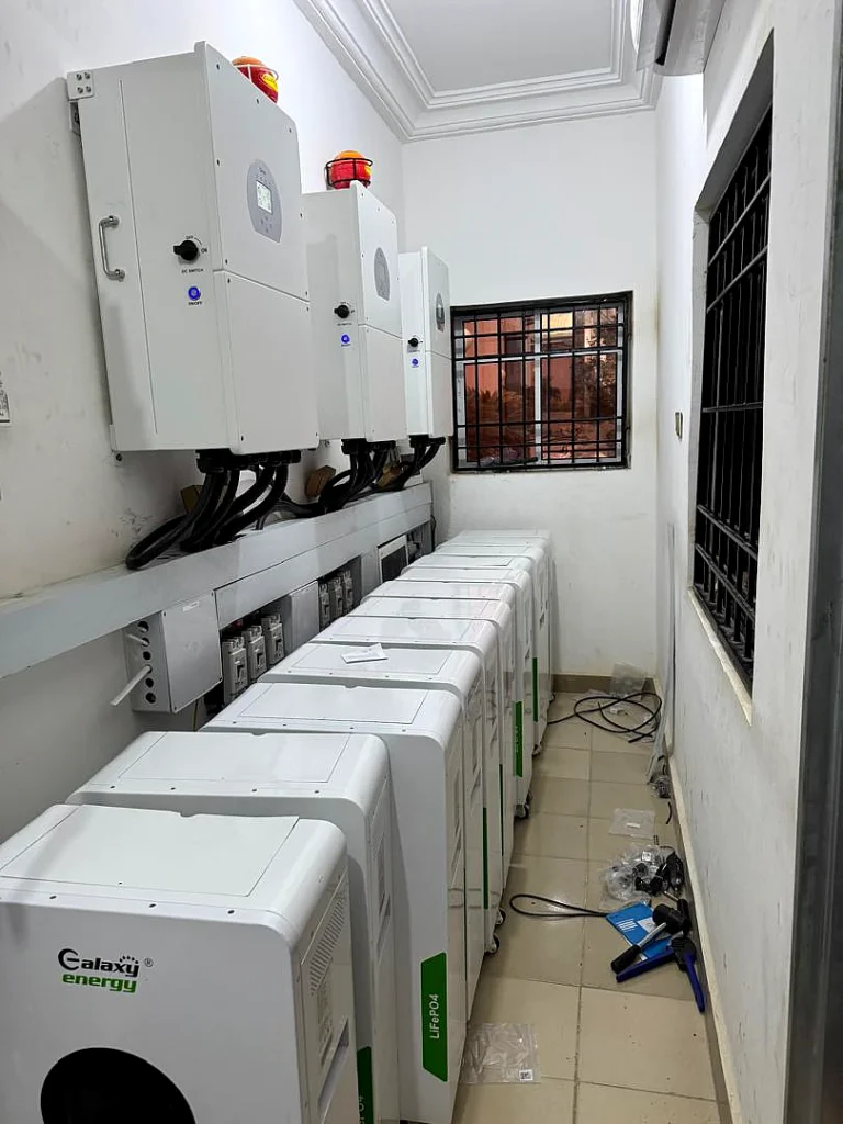 Row of Galaxy Energy lithium batteries and three hybrid inverters in a plant corridor