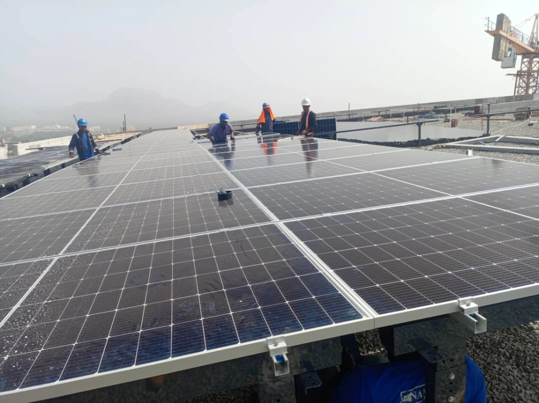 Installers laying panels on a flat roof with hills behind