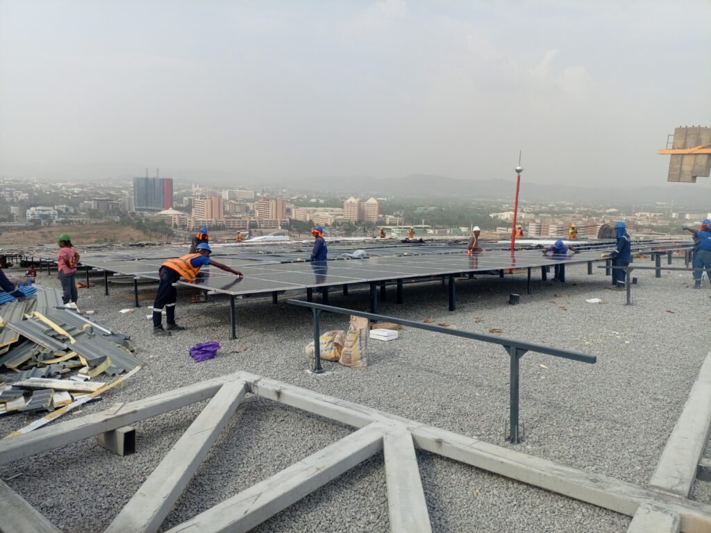 Wide view of the roof mid-install, mounting structure laid out and tower crane overhead