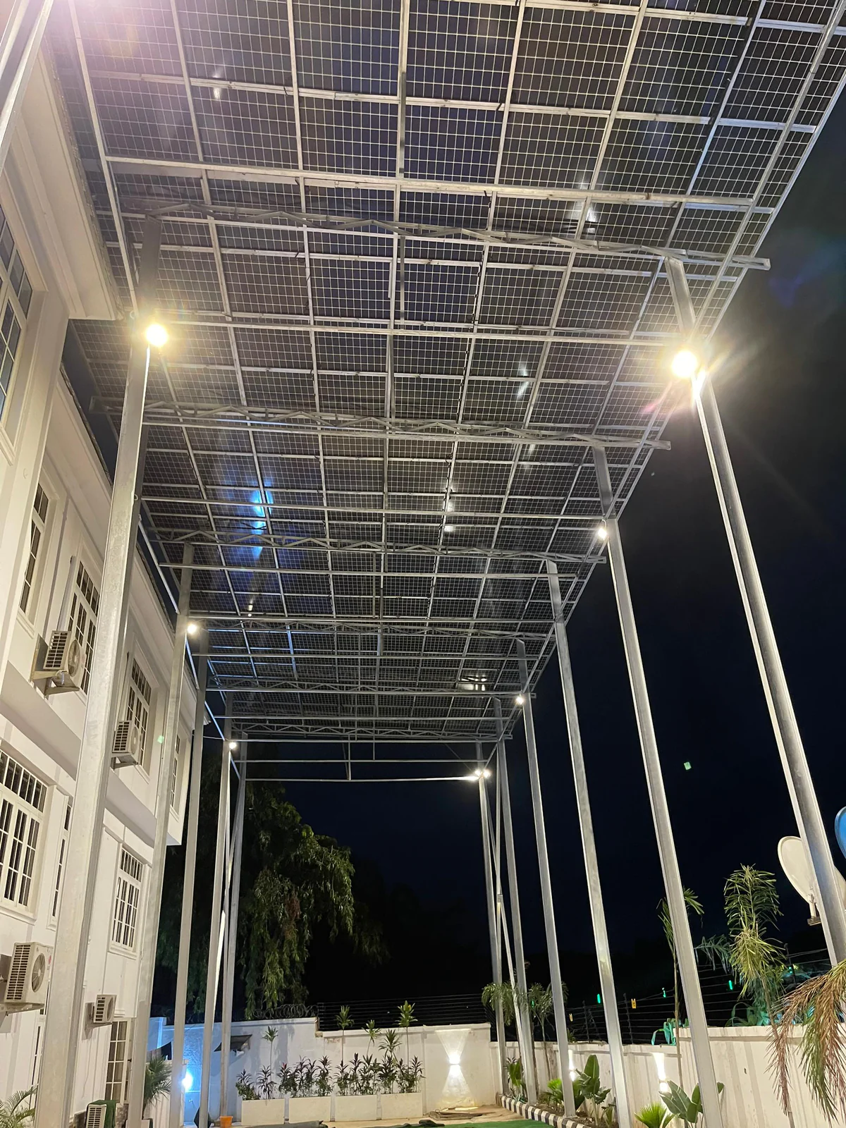 Solar carport lit at night with pole lights underneath